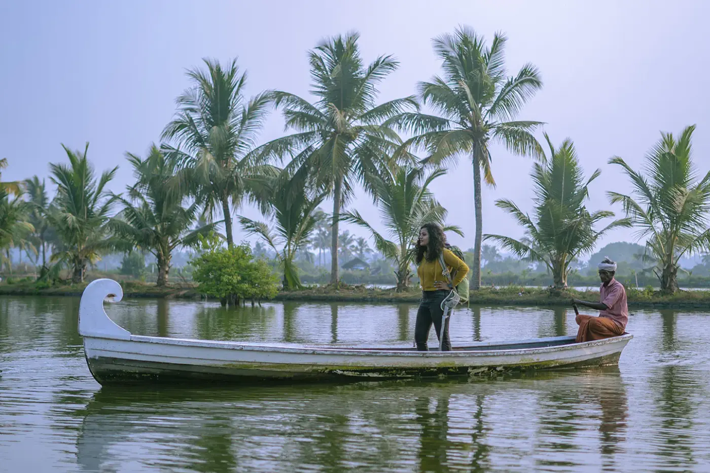 A traditional country boat gliding across the palm-lined backwater