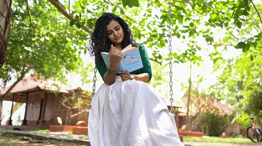Reading on a garden swing under the trees