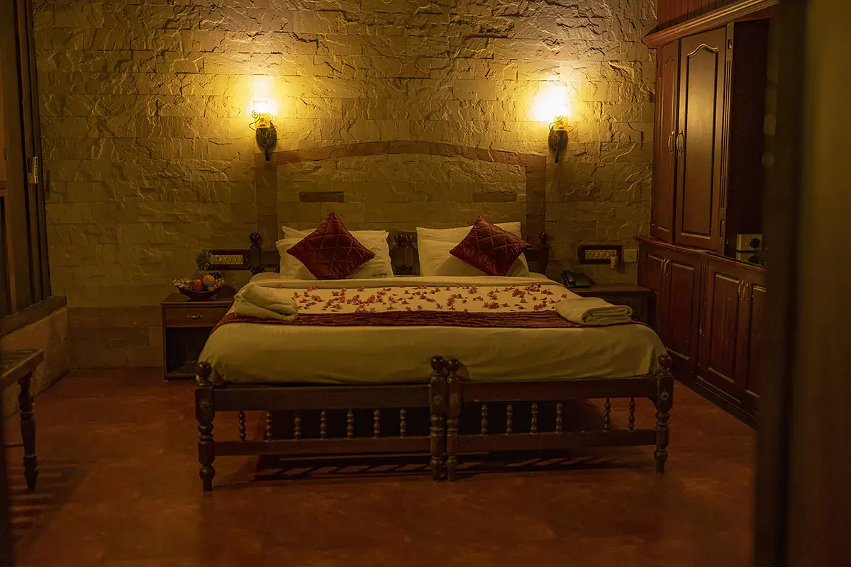 Deluxe Heritage Room with carved wooden bed and laterite walls